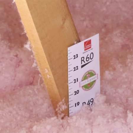 A measuring stick in pink insulation material showing its depth at 18 inches.